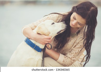 Portrait of beautiful young woman playing with dog on the sea shore