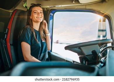 Portrait of beautiful young woman professional truck driver sitting in a big truck, looking at camera and smiling. Inside of vehicle. People and transportation concept. - Shutterstock ID 2182796935