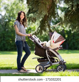 Portrait Of Beautiful Young Woman Pushing Baby Carriage In The Park