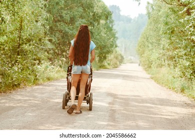 Portrait Of Beautiful Young Woman Pushing Baby Carriage In The Park