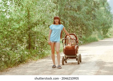 Portrait Of Beautiful Young Woman Pushing Baby Carriage In The Park