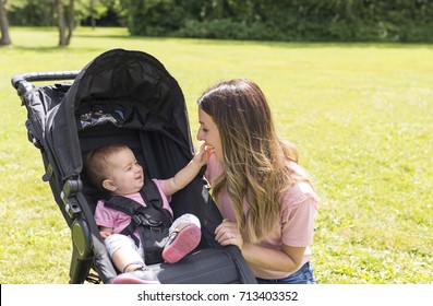 Portrait Of Beautiful Young Woman Pushing Baby Carriage In The Park