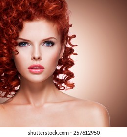 Portrait Of Beautiful Young Woman With Red Curly Hair  On Beige Background.