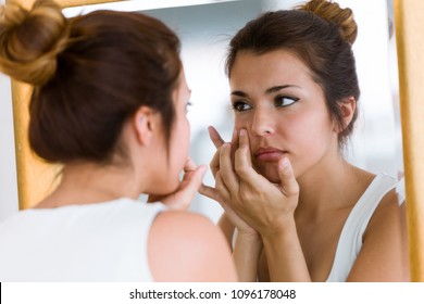 Portrait Of Beautiful Young Woman Removing Pimple From Her Face In A Bathroom Home.