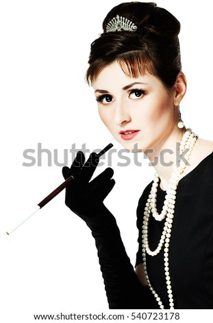 Portrait of a beautiful young woman in retro style with cigarette in mouthpiece in the image of the famous actress Audrey Hepburn. Isolated on white