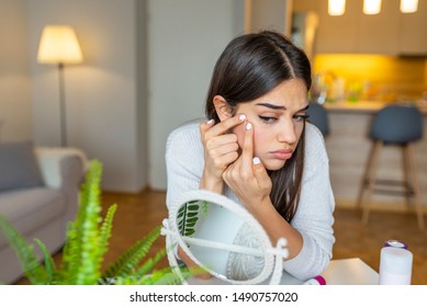 Portrait Of Beautiful Young Woman Squeezing Pimples While Looking At The Mirror. Pimple On Cheek. Young Woman Squeeze Her Acne In Front Of The Mirror. I'm Sure This Will Go Away If I Pop It.