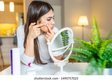 Portrait Of Beautiful Young Woman Squeezing Pimples While Looking At The Mirror. Pimple On Cheek. Young Woman Squeeze Her Acne In Front Of The Mirror. I'm Sure This Will Go Away If I Pop It.