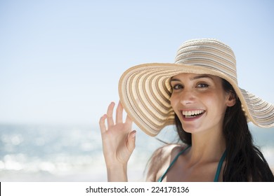 Portrait Of A Beautiful Young Woman In A Swimsuit On The Beach Protecting Herself From The Sun With A Big Hat