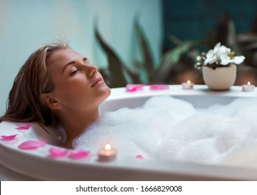 Portrait Of A Beautiful Young Woman Taking Bath With Foam By Candlelight, Enjoying Dayspa In Luxury Spa Hotel