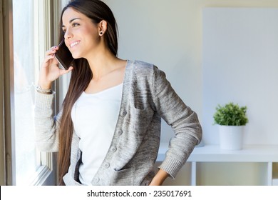 Portrait Of Beautiful Young Woman Talking On The Phone At Home.