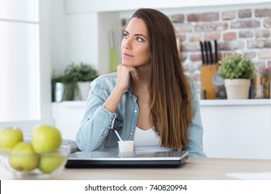 Portrait Of Beautiful Young Woman Thinking In The Kitchen.