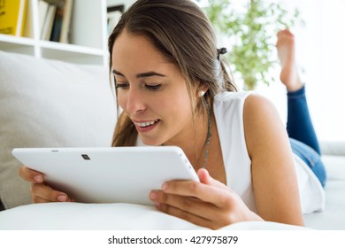 Portrait of beautiful young woman using her digital tablet at home.