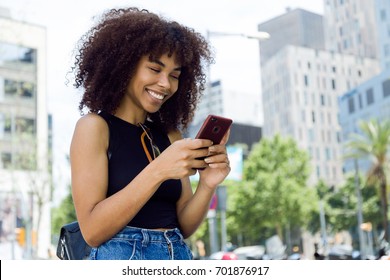 Portrait of beautiful young woman using her mobile phone in the street.