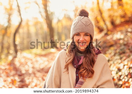 Portrait of a beautiful young woman walking through the forest on a sunny autumn day