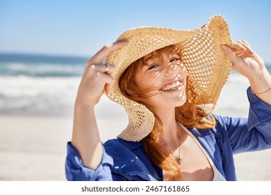 Portrait of beautiful young woman wearing straw hat with large brim at beach and looking at camera. Close up face of attractive smiling girl with freckles and red hair at seaside with copy space.  - Powered by Shutterstock