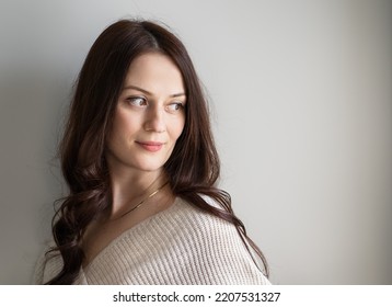 Portrait Of Beautiful Young Woman With White Skin And Wavy Hair In Front Of Isolated Wall Not Looking At Camera