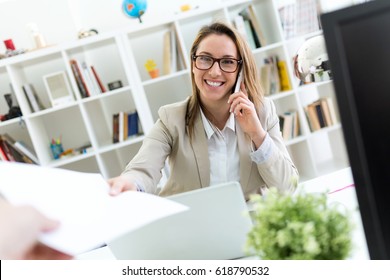 Portrait of beautiful young woman working with mobile phone in her office.