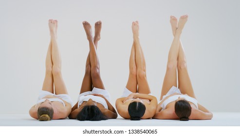 Portrait of beautiful young women of different ethnicities with perfect firm and slim bodies with hairless soft and silky legs crossed isolated on a white background.