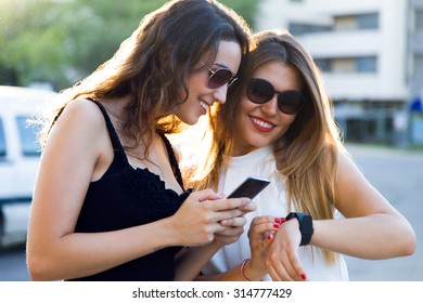 Portrait of beautiful young women using a smartwatch in the street.