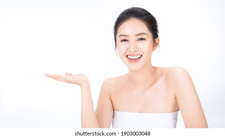 Portrait beauty asian woman fair perfect healthy glow skin.Girl show empty copy space on open hand palm for text. Proposing a product. Gestures for advertisement. Asia girl with pretty smile on face. 