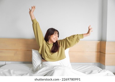 Portrait of beauty happy Asian woman awaking, wake up on the bed (sleep). Young beautiful Asian girl stretching her arms in fresh early morning, relax peaceful morning routine yawn concept banner - Powered by Shutterstock