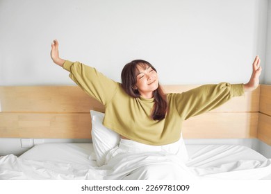 Portrait of beauty happy Asian woman awaking, wake up on the bed (sleep). Young beautiful Asian girl stretching her arms in fresh early morning, relax peaceful morning routine yawn concept banner - Powered by Shutterstock