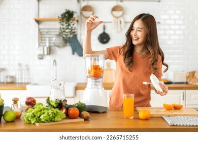 Portrait of beauty healthy asian woman making orange fruit smoothie with blender.young girl preparing cooking detox cleanse and with fresh orange juice in kitchen at home.Diet concept.healthy drink