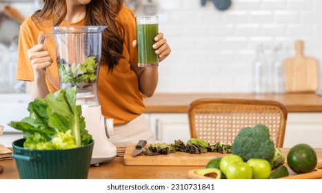 Portrait of beauty healthy asian woman making green vegetables detox clean and green fruit smoothie with blender.young girl drinking glass of green fruit smoothie in kitchen.Diet concept.healthy drink - Shutterstock ID 2310731841