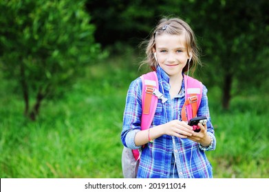 Portrait of beauty pre-teen tween kid girl with long brunette hair wearing pink  rucksack with headphones listening to music outside 