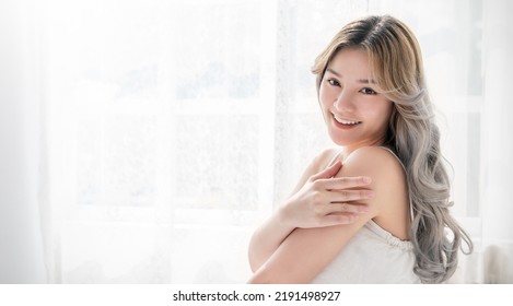 Portrait Of Beauty Smile Asian Woman Applying Lotion To Arm Shoulder Skin During Morning Routine. Cute Asian Girl Face. Skincare Body Lotion, Beauty Clinic Skincare Spa, Indoors Woman Lifestyle 