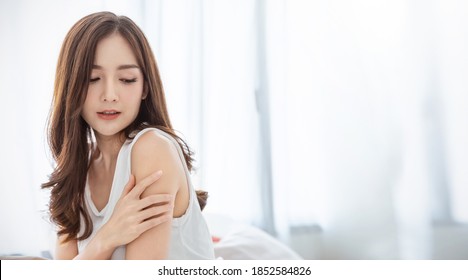 Portrait of beauty  smiling asian woman applying a lotion to her arm skin during her morning routine. Cute asian girl. Skincare body lotion, beauty clinic skincare spa, indoors woman lifestyle concept
