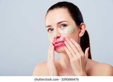 Portrait of beauty woman with natural make-up applying blue hyaluronic hydrogel patches and pink lips mask. Female face with mask under eyes. Korean cosmetics. 