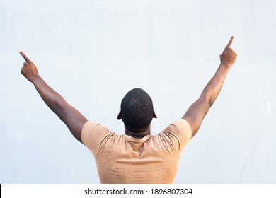Portrait from behind African American man with arms raised and fingers pointing up