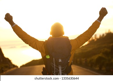 Portrait from behind of hiker with arms raised during sunset - Powered by Shutterstock