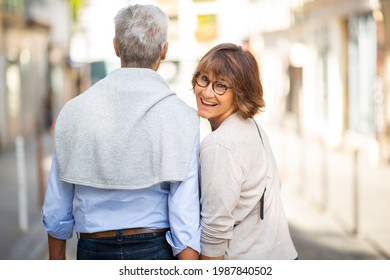 Portrait From Behind Older Couple Walking Together On Street