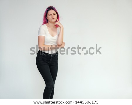 Portrait below the knee of a young beautiful girl teenager in a white T-shirt and black jeans with beautiful purple hair on a white background in the studio. They say, they smile, they show hands
