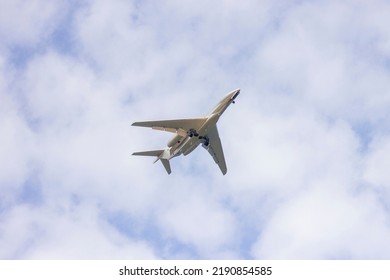 A Portrait From Below Of A Private Plane Flying In A Cloudy Sky. The Jet Plane Has Started To Descend For Landing And The Wheels Are Out.