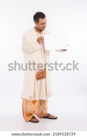 Portrait of bengali man in traditional clothing holding blank placard on occasion of durga puja celebration
