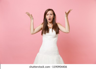 Portrait of bewildered shocked bride woman in beautiful white wedding dress standing and spreading hands isolated on pink pastel background. Wedding celebration concept. Copy space for advertisement - Powered by Shutterstock