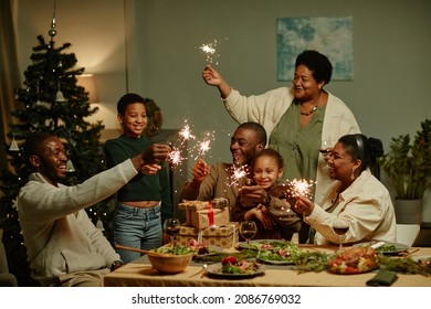 Portrait of big African-American family lighting sparklers while enjoying Christmas at home together - Powered by Shutterstock