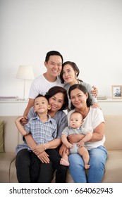 Portrait Of Big Asian Family Posing For Photo At Home Sitting On Sofa, All Smiling Happily Looking At Camera