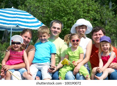 Portrait Of Big Family  With Their Little Daughter Under Beach Umbrella