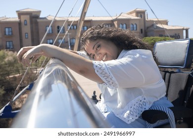 Portrait of a biracial girl posing on a bridge smiling in a wheelchair - Powered by Shutterstock