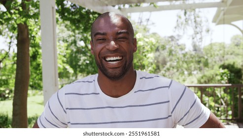 Portrait of a biracial man enjoying his time in a garden, looking at the camera and smiling, on a sunny day, in slow motion - Powered by Shutterstock