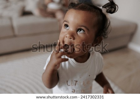 Portrait of biracial toddler girl in room. Afro-Caucasian little girl. Concept of interracial family.