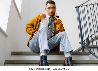 Portrait of biracial transgender man sitting on stairs and looking at camera. Gender, fashion and lifestyle, unaltered. - Powered by Shutterstock