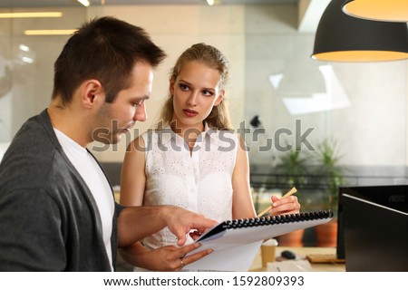 Portrait of biz people planning work. Serious cute woman in white blouse showing documents and discussing with businessman new project. Teamwork and business concept