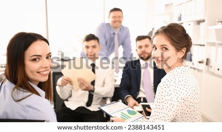 Portrait of biz people sitting in big modern office and looking at camera with joy. Woman holding paper folder with important documents that determine corporation future. Company meeting concept