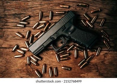 Portrait of a black 9mm pistol on an old wooden floor with 9mm ammunition next to it. top view
