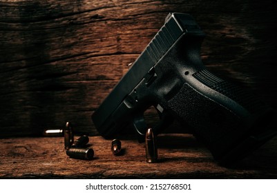 Portrait of a black 9mm pistol on an old wooden floor with 9mm ammunition next to it
